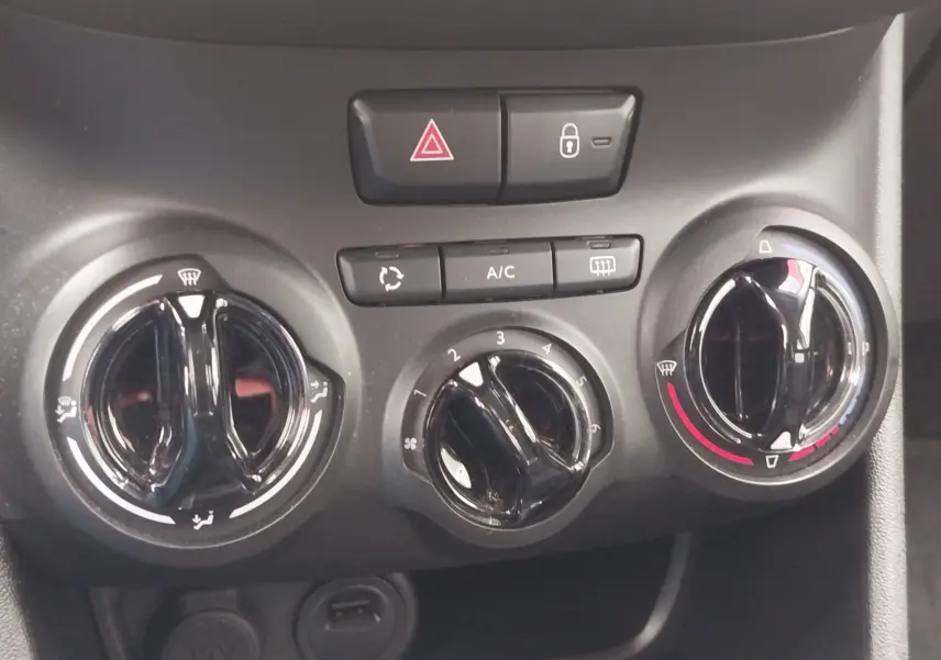 Détail des commandes de climatisation et sécurité du tableau de bord d'une Peugeot 208 noire, version diesel 2019.