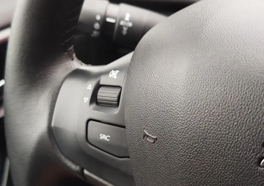 Gros plan sur le volant noir de la Peugeot 208 2019, montrant les commandes audio et le bouton SRC.