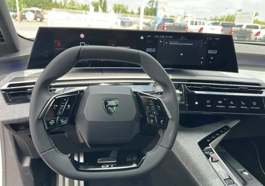 Vue intérieure centrée sur le volant cuir multifonctions du Peugeot 5008 Hybrid 145 GT avec tableau de bord numérique.
