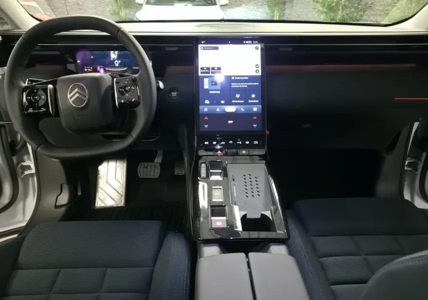 Vue intérieure avant du Citroën C5 Aircross blanc, tableau de bord noir avec écran tactile vertical et sièges tissu bleu.