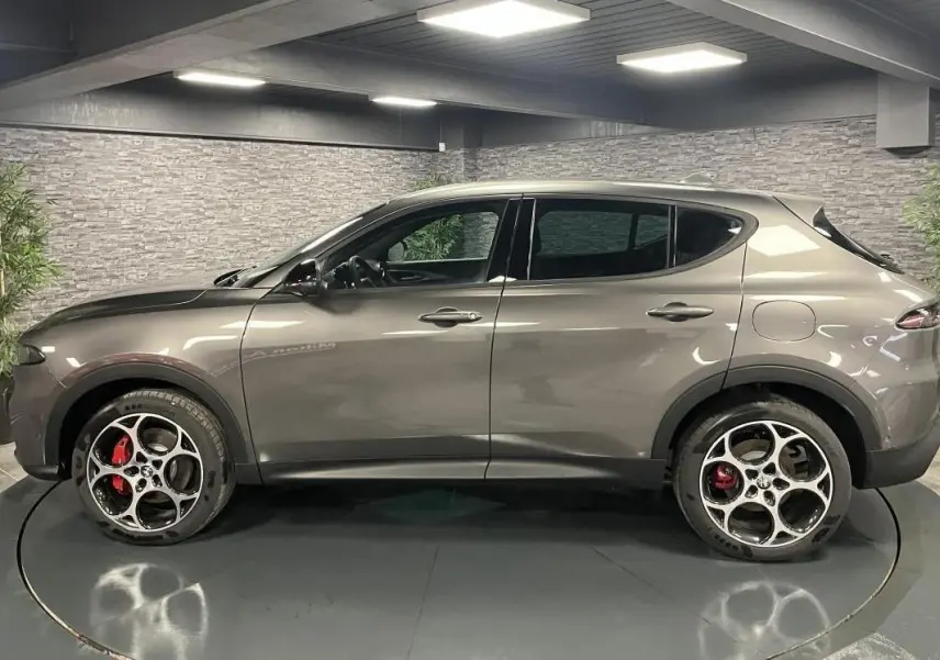 Profil droit d'un Alfa Romeo Tonale gris foncé 2023 avec jantes alliage 19 pouces et étriers rouges visibles.