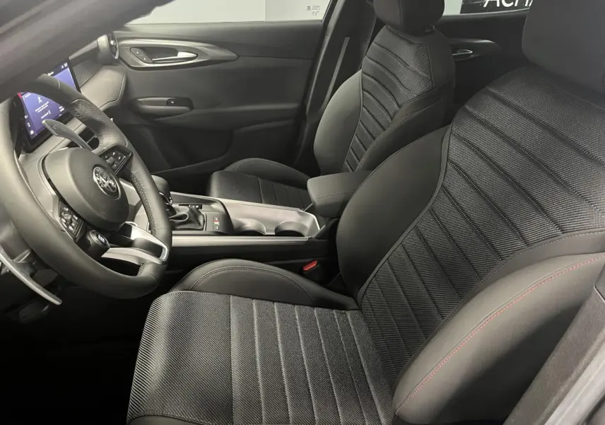 Intérieur de l'Alfa Romeo Tonale 2023, vue côté conducteur, sellerie noire AlfaTec avec surpiqûres rouges et volant sport cuir.