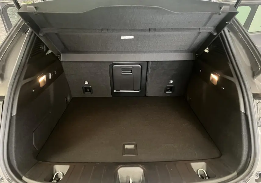 Coffre ouvert d'un Alfa Romeo Tonale gris foncé, vue intérieure montrant un espace de chargement propre et éclairé.