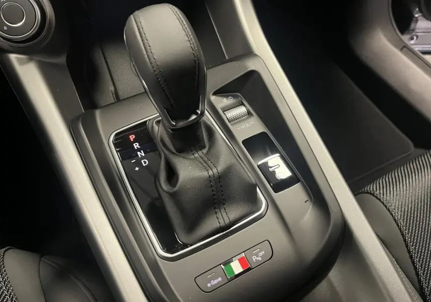 Gros plan sur la console centrale de l'Alfa Romeo Tonale 2023, levier de vitesse cuir et bouton aux couleurs italiennes.