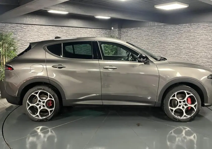 Profil côté gauche de l'Alfa Romeo Tonale gris foncé 2023 avec jantes alliage 19 pouces et étriers rouges visibles.