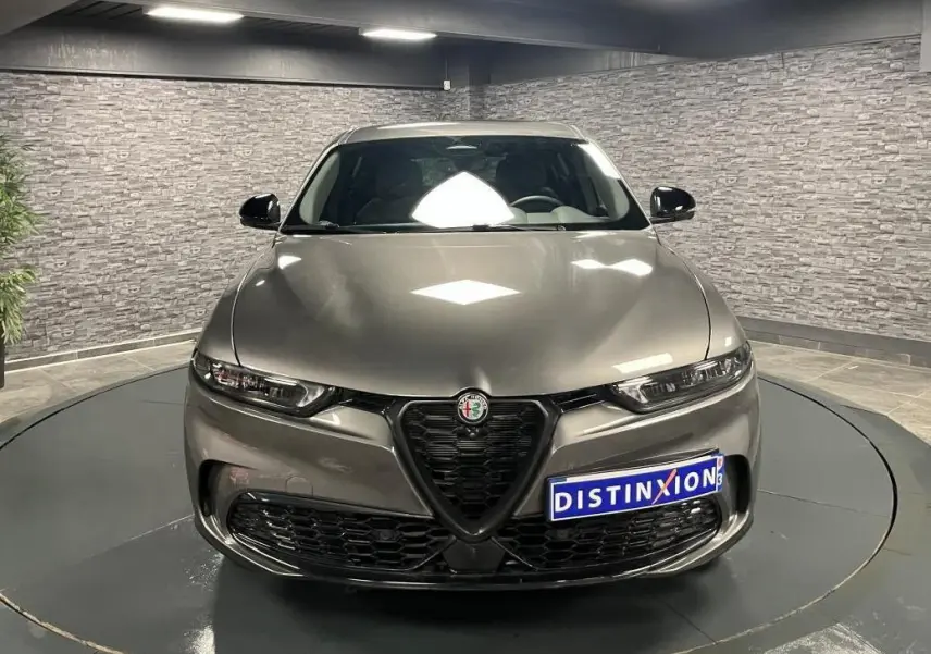 Vue frontale d'une Alfa Romeo Tonale gris foncé avec calandre en V et phares LED dans un showroom.