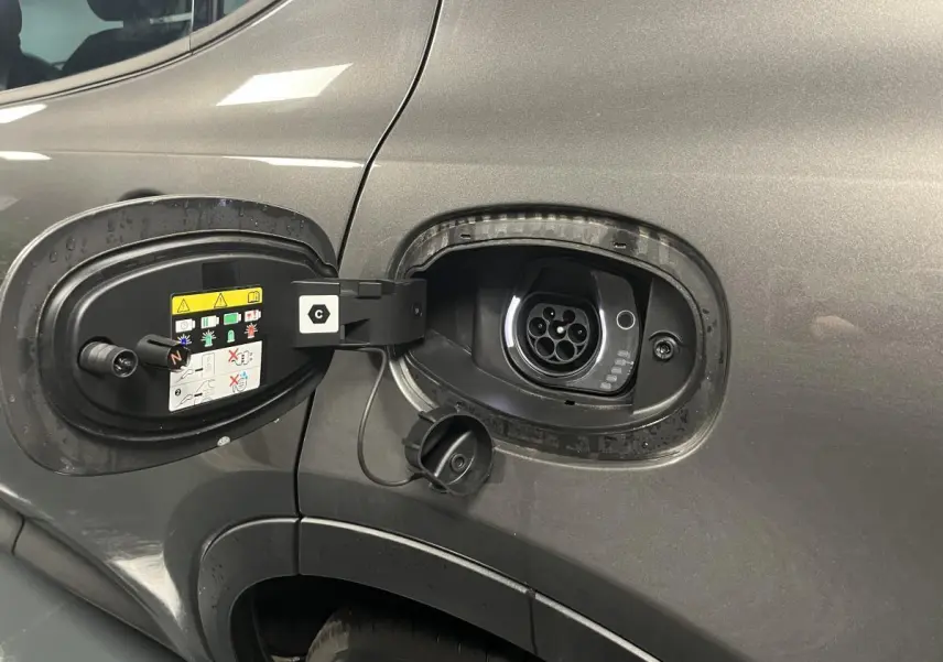 Prise de recharge hybride ouverte côté gauche sur Alfa Romeo Tonale gris foncé, avec port de charge visible.