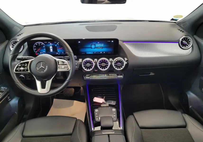 Intérieur avant d'une Mercedes GLA 200 D Business Line 2022, tableau de bord noir avec éclairage d'ambiance violet et écran tactile large.