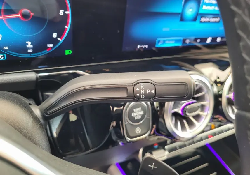 Gros plan intérieur sur la commande de boîte automatique et le tableau de bord numérique du Mercedes GLA 200 D bleu.