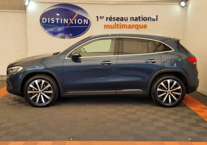 Profil latéral droit d'un Mercedes GLA 200 D Business Line bleu, avec jantes alliage et vitres teintées en showroom.