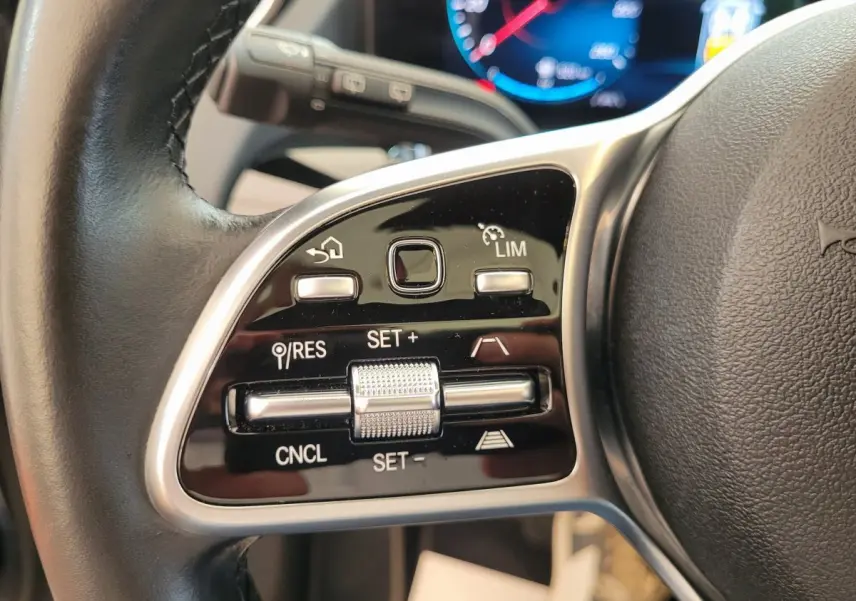 Gros plan sur les commandes du volant cuir noir du Mercedes GLA 200 D Business Line 2022, avec affichage digital en arrière-plan.