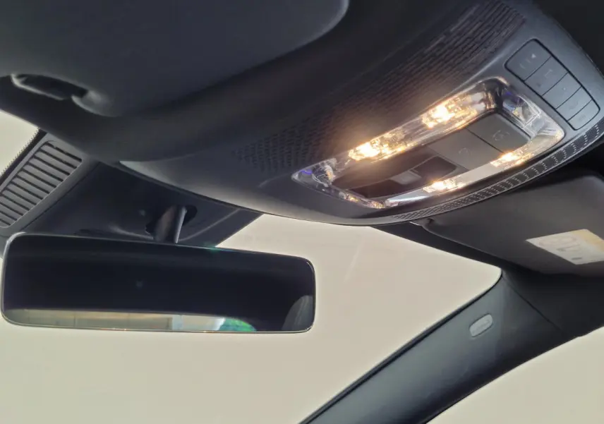 Plafonnier allumé et rétroviseur intérieur noir dans l'habitacle sombre d'un Mercedes GLA 200 D bleu 2022.