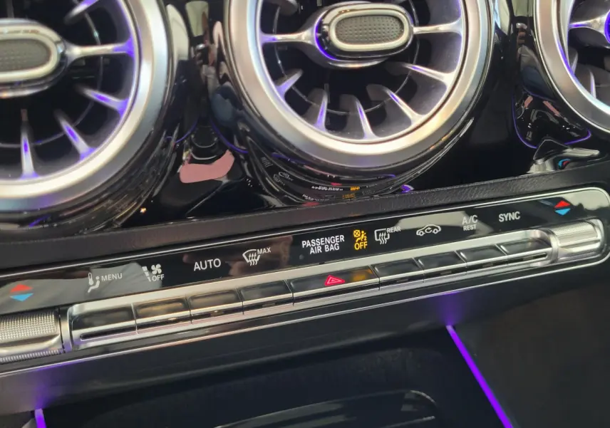 Gros plan sur les aérateurs ronds chromés et la console de climatisation digitale du Mercedes GLA 200 D bleu.
