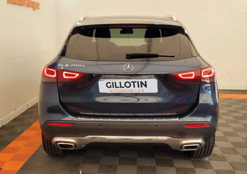 Vue arrière d'un Mercedes GLA 200d bleu 2022 avec feux LED allumés et double sortie d'échappement chromée.