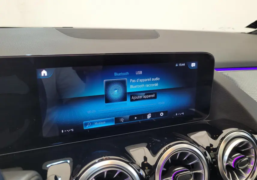 Écran tactile multimédia affichant Bluetooth et USB, avec aérateurs ronds et ambiance lumineuse violette sur tableau de bord noir.
