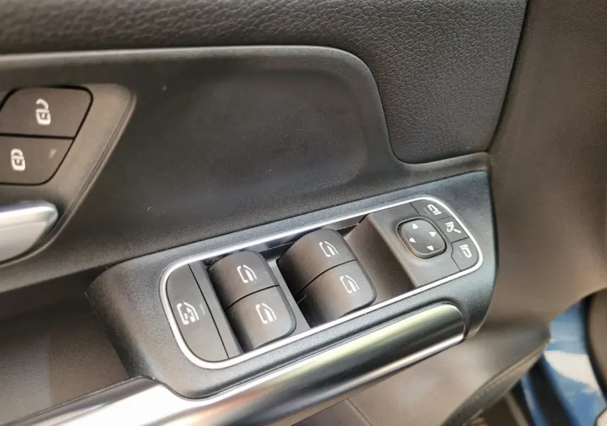 Gros plan sur les commandes de lève-vitres et rétroviseurs côté conducteur du Mercedes GLA 200 D Business Line bleu 2022.