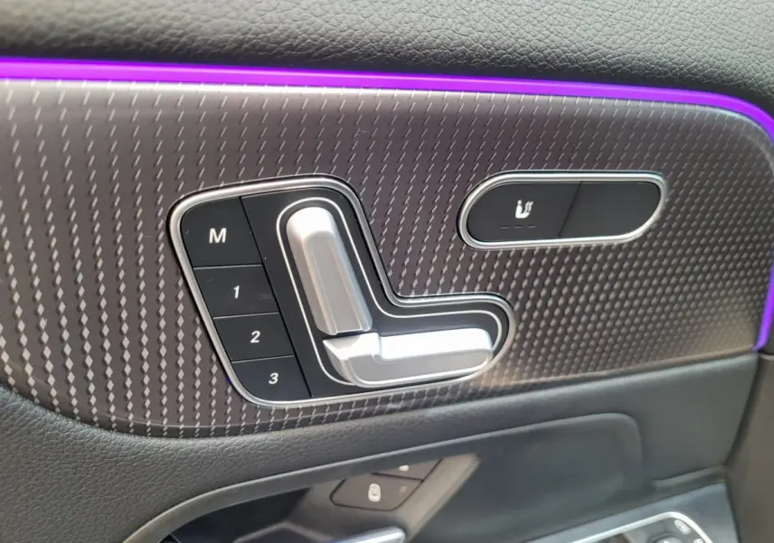 Détail des commandes de réglage électrique et mémoire des sièges sur la porte côté gauche d'un Mercedes GLA 200 D bleu 2022.