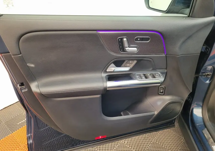 Porte côté gauche ouverte d'un Mercedes GLA 200 D Business Line bleu, avec commandes de siège et vitres intégrées.