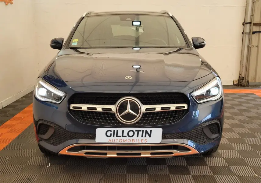 Vue frontale d'un Mercedes GLA 200 D Business Line bleu avec calandre chromée et phares LED allumés.