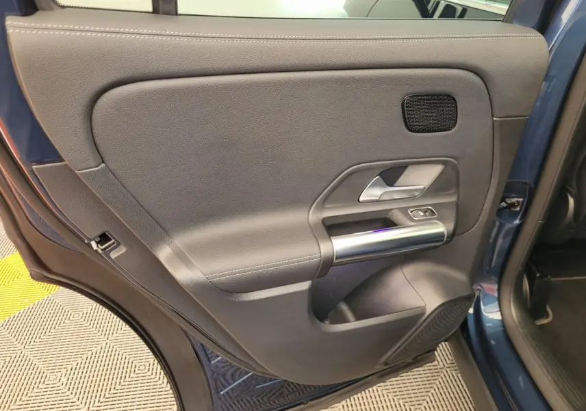 Gros plan sur la porte arrière gauche bleu foncé du Mercedes GLA 200 D avec garniture grise et poignée argentée.
