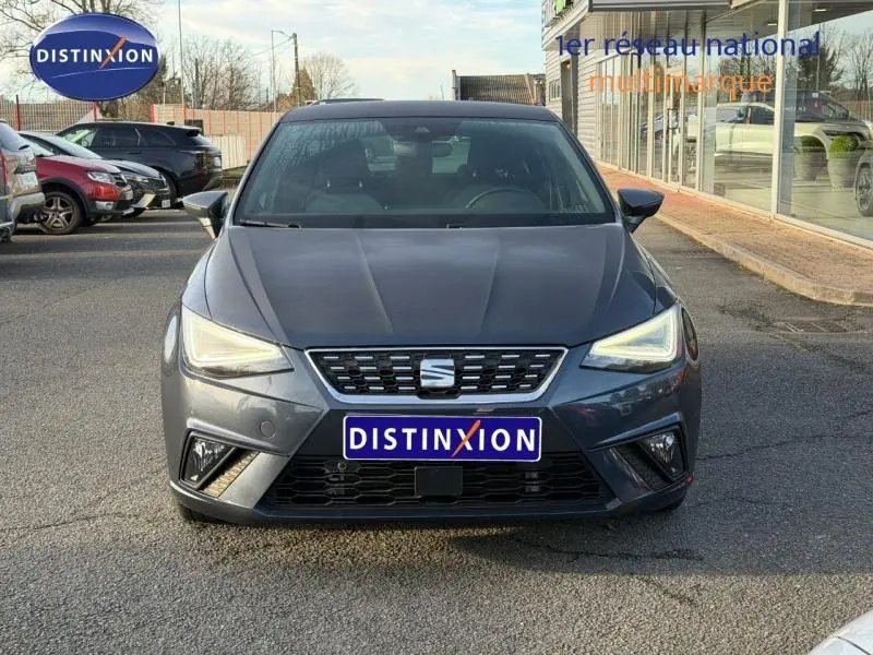 Vue de face d'une SEAT Ibiza 2025 gris magnétique métallisé avec phares allumés et calandre distinctive au centre.