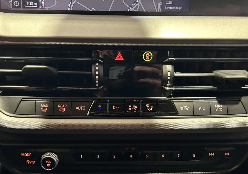 Vue rapprochée du tableau de bord noir de la BMW Série 1 116d 2023, montrant les commandes de climatisation et ventilation.