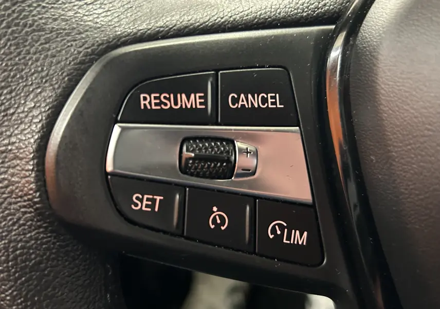 Gros plan sur les commandes de régulateur de vitesse au volant d’une BMW Série 1 116d noire de 2023.