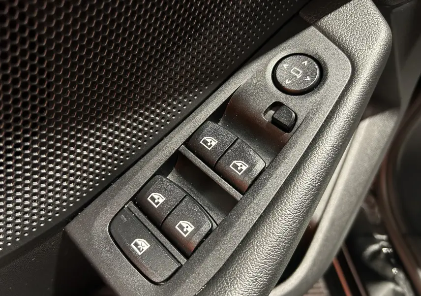 Gros plan sur les commandes de lève-vitres et réglage des rétroviseurs côté conducteur d’une BMW Série 1 noire.