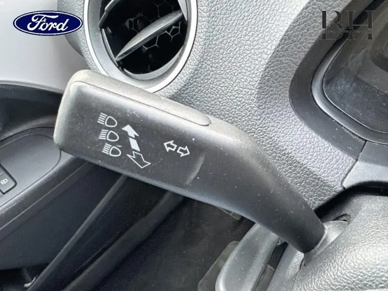 Le levier de clignotant noir en gros plan à gauche du volant dans l'habitacle d'une Volkswagen Up blanche.