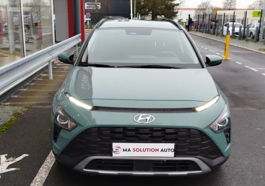 Vue frontale d'un Hyundai Bayon 2022 vert Elemental Brass Metal avec calandre noire et feux LED allumés.