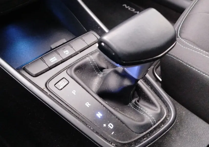 Gros plan sur la commande de la boîte automatique de la Hyundai Bayon 2022, avec éclairage bleu et coutures vertes.