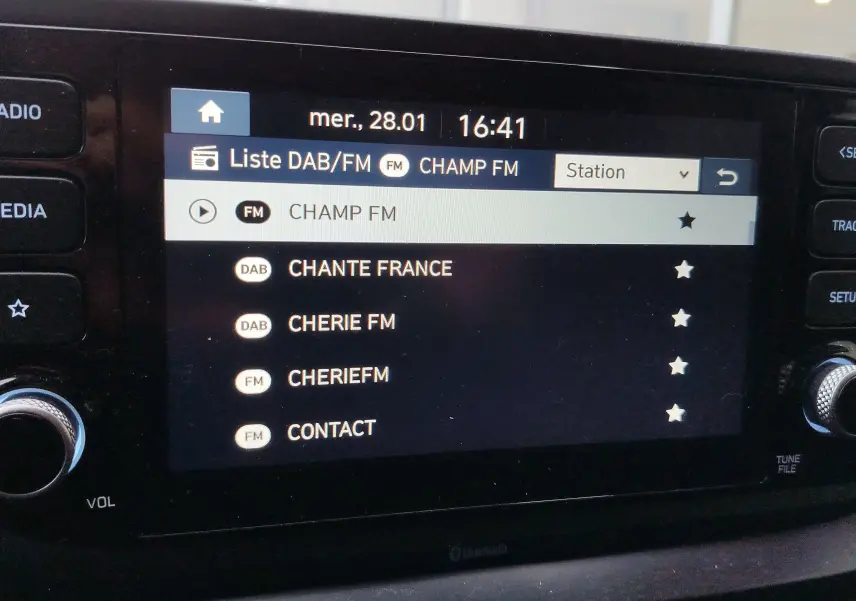 Écran central tactile du Hyundai Bayon 2022 montrant la liste des stations radio DAB/FM avec interface noire et boutons latéraux.