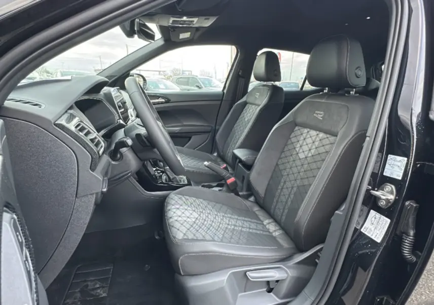 Vue intérieure côté conducteur du Volkswagen T-Cross noir intense, sièges R-Line en tissu et alcantara avec surpiqûres contrastées.