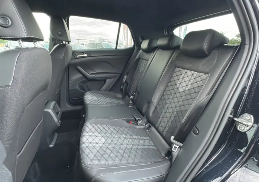 Vue intérieure côté droit montrant la banquette arrière tissu noir avec motifs géométriques du Volkswagen T-Cross noir intense 2025.