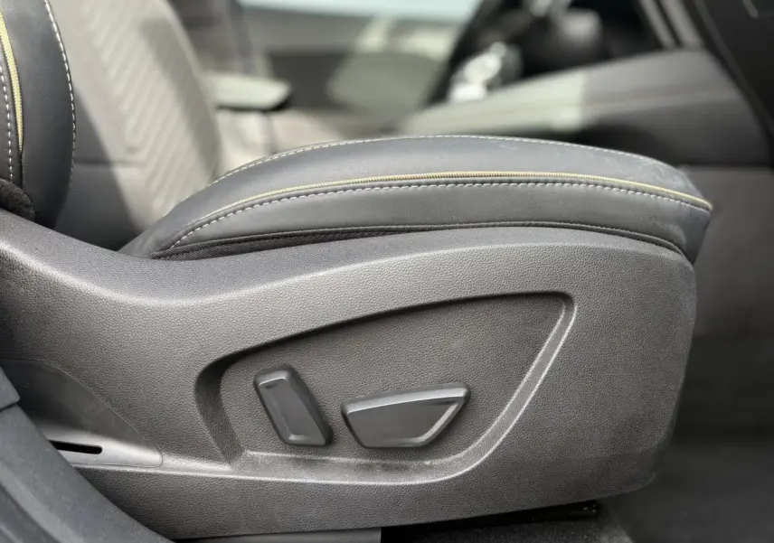 Gros plan sur les commandes de réglage électrique du siège avant droit en cuir noir avec surpiqûres jaunes du Renault Symbioz.