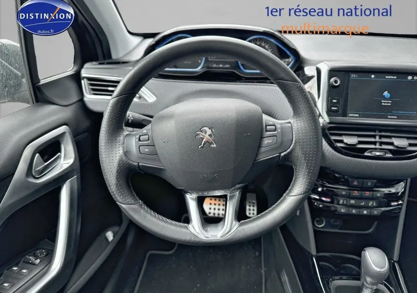 Vue rapprochée du volant en cuir noir et du tableau de bord moderne d'une Peugeot 2008 gris platinium de 2019.