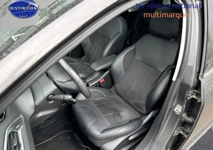 Vue intérieure côté conducteur d'un Peugeot 2008 gris platinium, sièges en cuir noir avec surpiqûres grises.