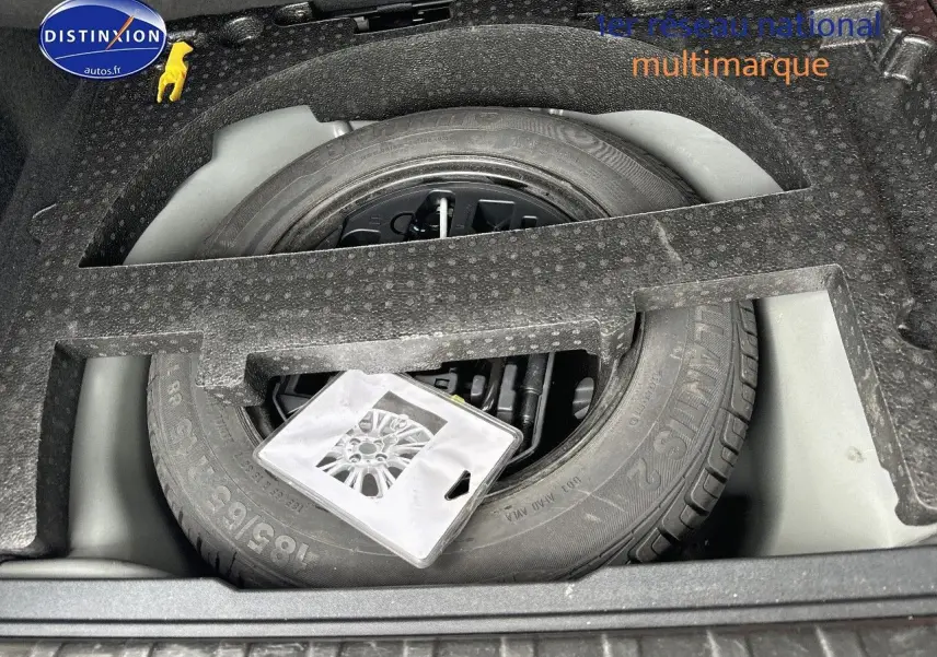 Vue en plongée sur la roue de secours et le rangement en mousse dans le coffre du Peugeot 2008 gris platinium.