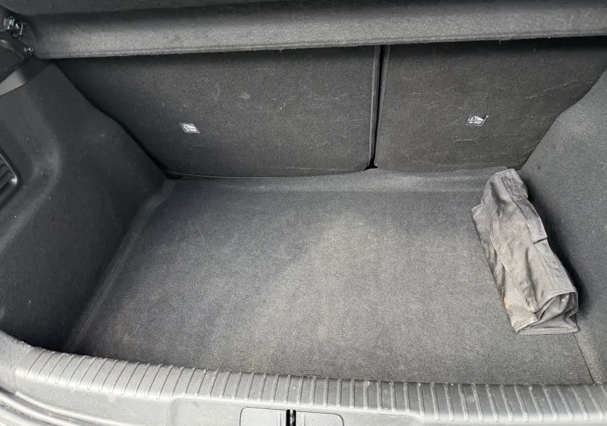 Coffre spacieux et propre du DS3 2024 gris laqué, avec un sac noir roulé posé à droite.