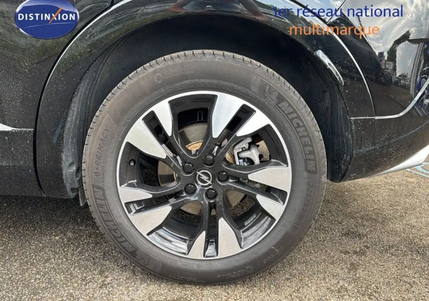 Gros plan sur la roue avant gauche noire de l'Opel Grandland 1.6 Turbo 225ch Hybride GS avec jante bi-ton distinctive.
