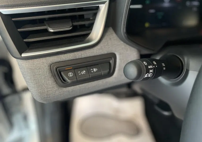 Détail des commandes d'éclairage et verrouillage sur la gauche du tableau de bord gris tissu de la Renault Clio 2025 blanche