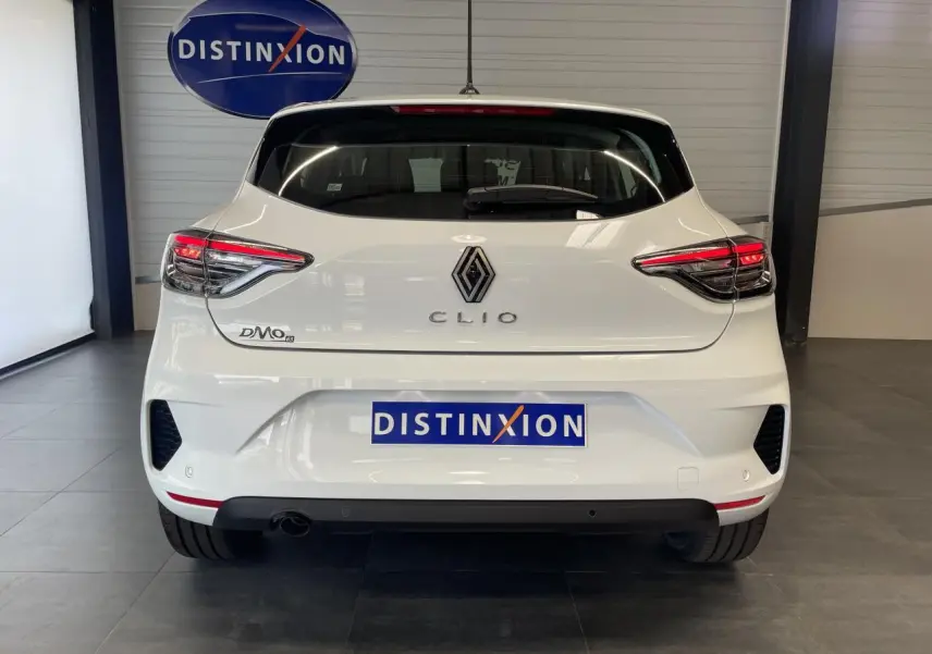 Vue arrière d'une Renault Clio blanche 2025 avec feux LED et logo chromé dans un showroom.