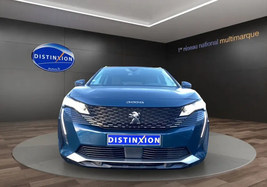 Peugeot 3008 Bleu Célèbes vue de face en intérieur, avec calandre distinctive et phares allumés.