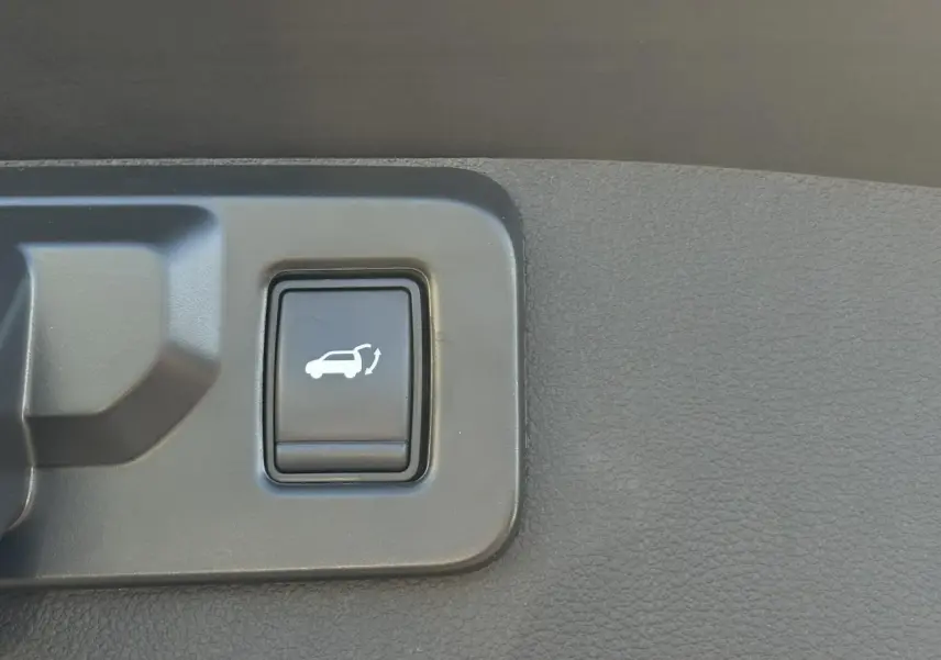 Gros plan sur le bouton d'ouverture du hayon mains libres dans l'habitacle du Renault Symbioz gris Cassiopée.