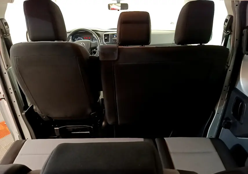 Vue intérieure arrière du Toyota Proace Verso 2019 montrant les sièges noirs et le tableau de bord gris clair.
