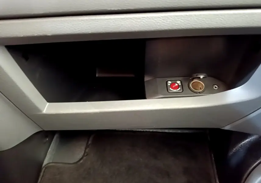 Gros plan sur la boîte à gants grise du Toyota Proace Verso 2019 avec prise 12V et commande rouge visible.