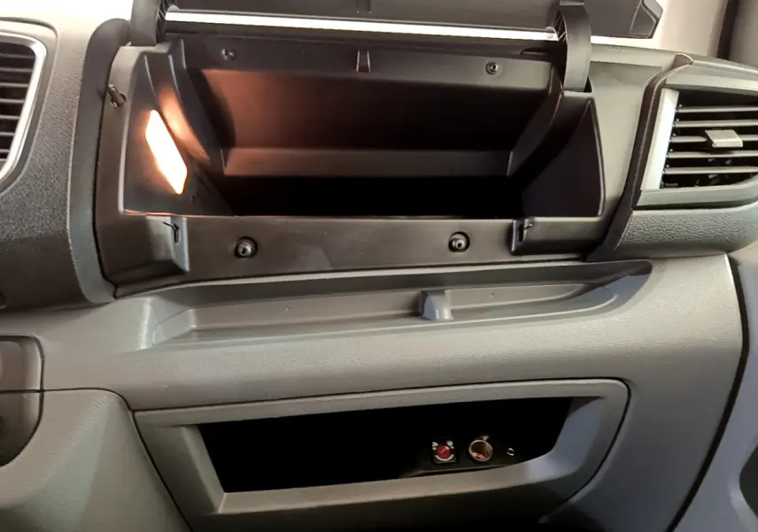 Intérieur du Toyota Proace Verso 2019 montrant la boîte à gants ouverte et le rangement inférieur gris clair côté passager.