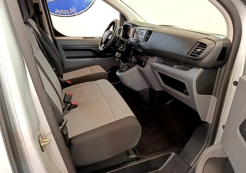 Intérieur avant droit du Toyota Proace Verso gris clair 2019 avec sièges bicolores et tableau de bord fonctionnel.