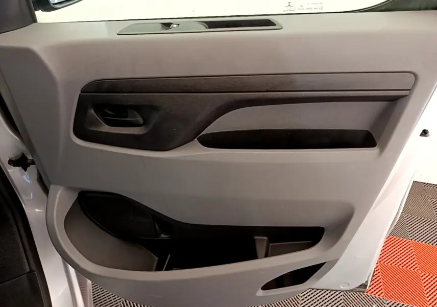 Gros plan sur la porte intérieure côté conducteur du Toyota Proace Verso gris clair, avec poignée noire et rangements intégrés.