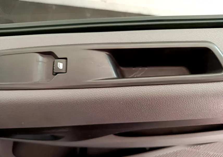 Gros plan sur la poignée intérieure et le bouton de verrouillage de porte du côté conducteur d’un Toyota Proace Verso gris clair.